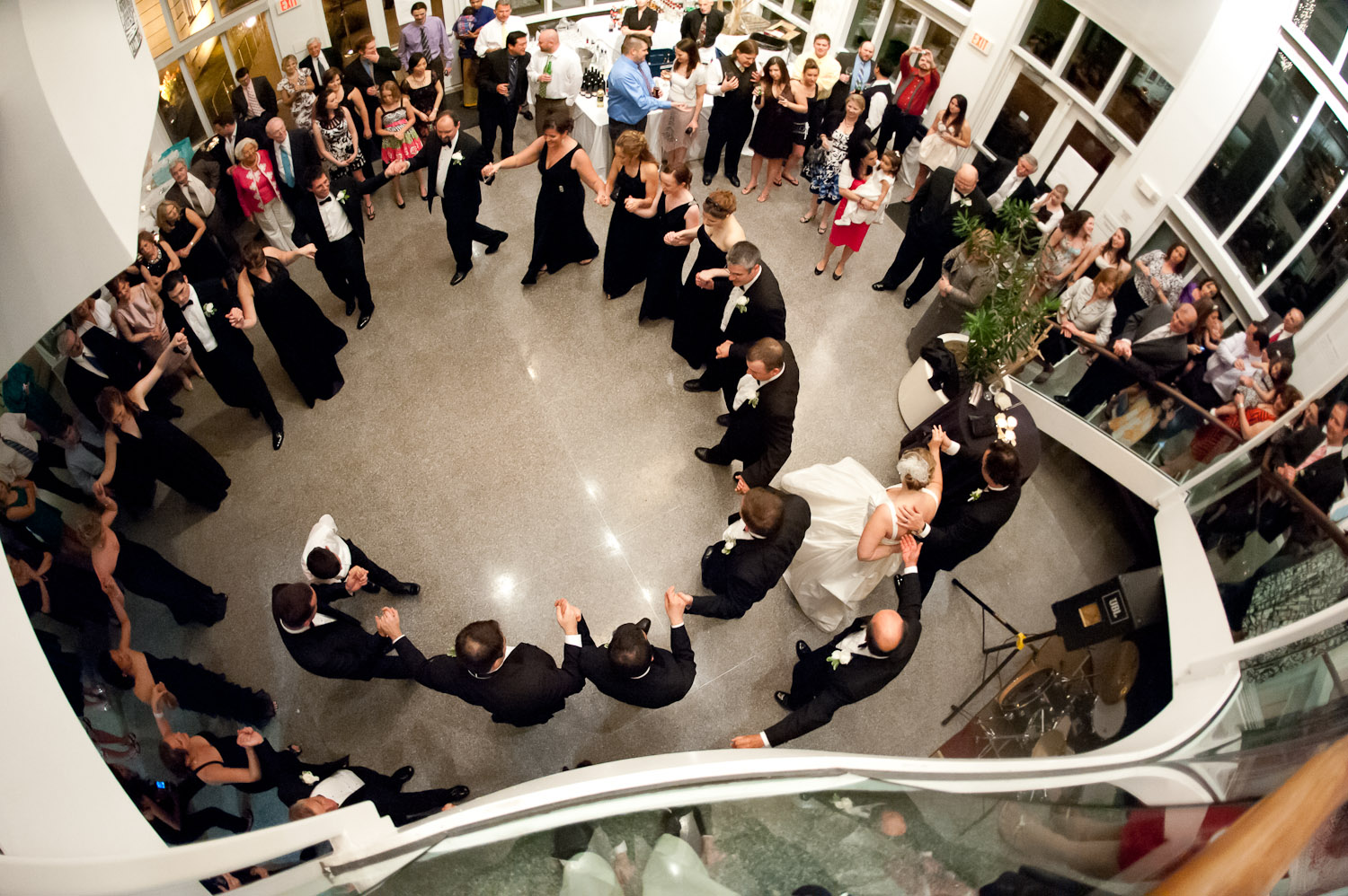 Birdseye view of the pavilion with a large group of wedding guests dancing in a circle formation