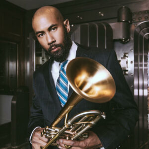 Man wearing a suit poses with a trumpet