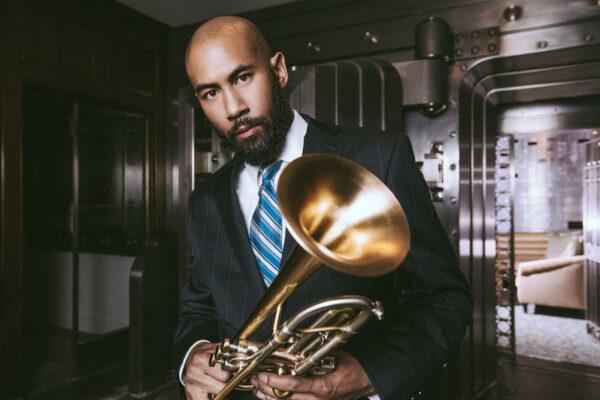 Man wearing a suit poses with a trumpet