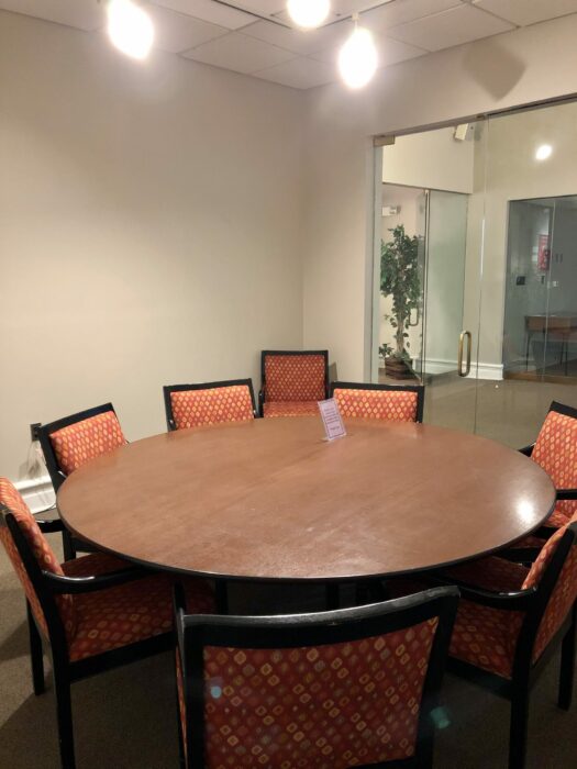 Chairs are positioned around a circular conference table in an empty room