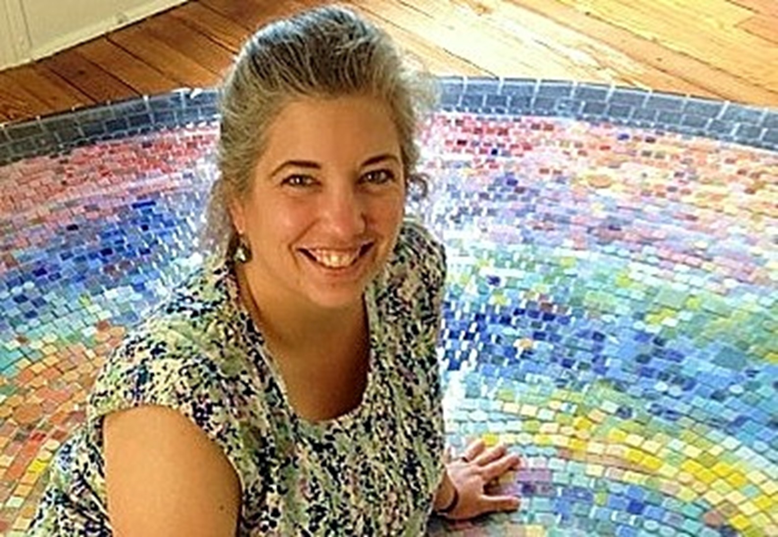 A woman sits on a large circular mosaic on the floor