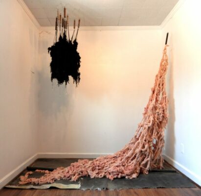 Installation art: A large clump of black fibre hangs from the ceiling and another fibre tangly mess hangs from the wall and drapes on the floor