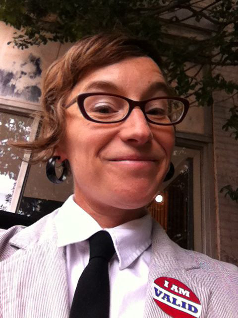 Selfie of a person wearing a suit and tie with a sticker on the lapel that reads "I am valid"