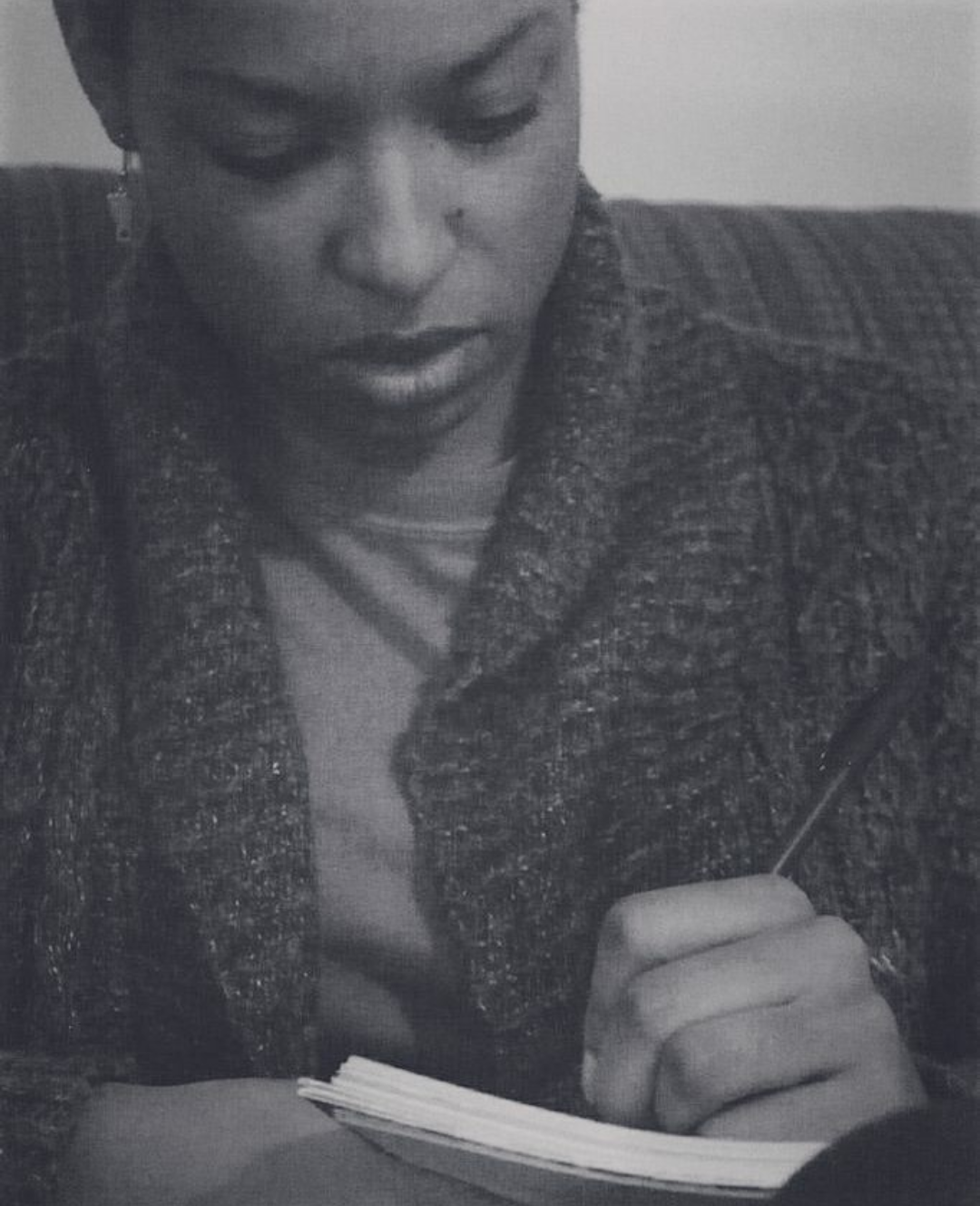 Black and white closeup of a woman writing in a notebook
