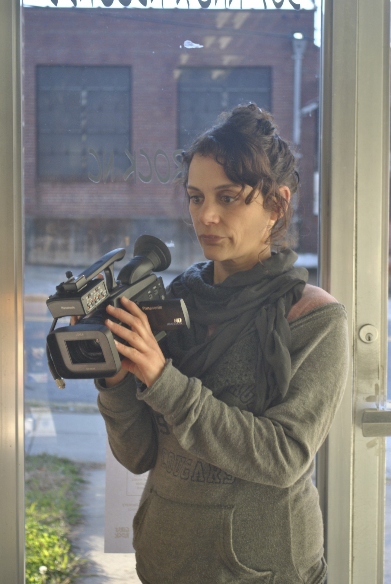 A woman uses a handheld video camera and looks into the viewfinder